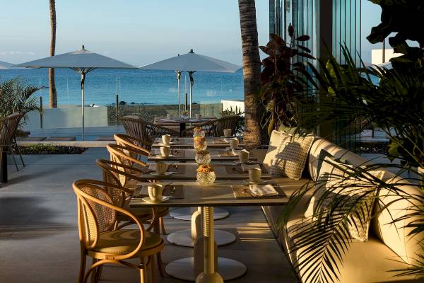 Außenbereich des Plus Fariones Suite Hotel mit Tischen, Stühlen und Sonnenschirmen.