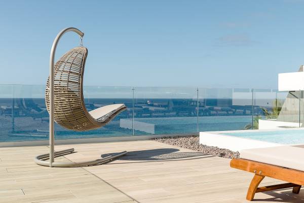 Außenterrasse mit Korbsessel und Poolblick im Plus Fariones Suite Hotel.