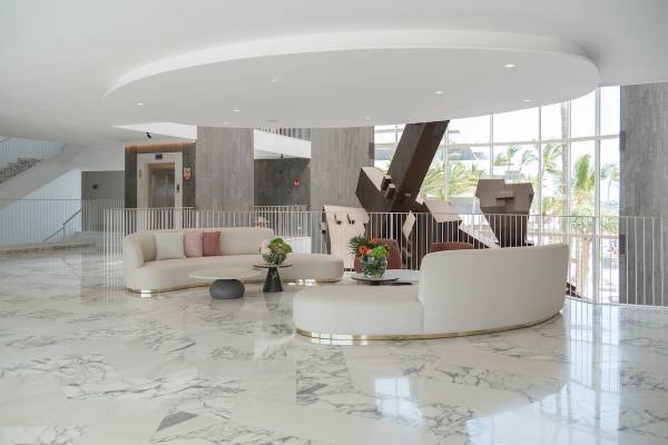 Empfangsbereich des Plus Fariones Suite Hotel mit weißen Möbeln und Marmorboden.