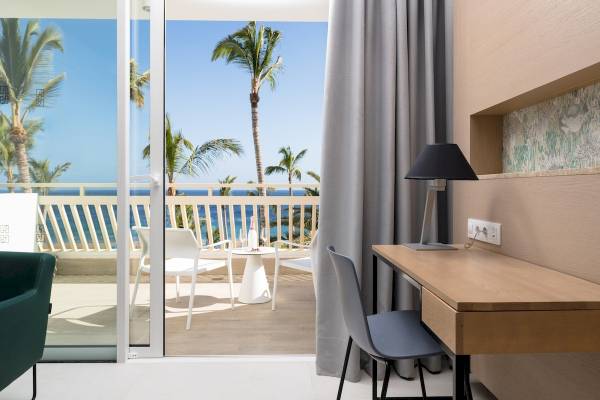 Innenansicht eines Zimmers im Plus Fariones Suite Hotel mit Blick auf einen Balkon und Meer