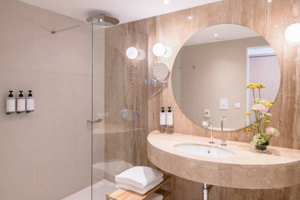 Badezimmer im Plus Fariones Suite Hotel mit Dusche, Waschbecken und Spiegel.