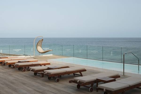 Terrasse des Plus Fariones Suite Hotel mit Sonnenliegen und Pool, Blick auf das Meer.