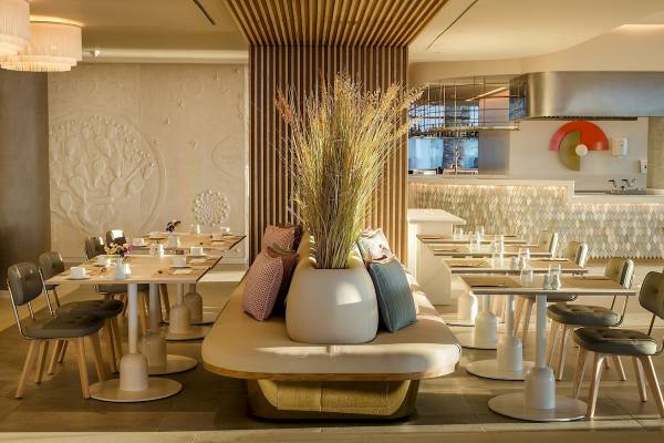 Innenbereich des Plus Fariones Suite Hotel Restaurants mit modernen Möbeln und dekorativen Pflanzen.