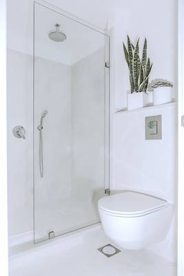 Ein Badezimmer mit einer Duschkabine und einem Toilettensitz in Weiß.