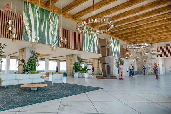 Lobby des Fariones Hotels mit moderner Einrichtung, grünen Pflanzen, Holzbalken und Kronleuchtern.