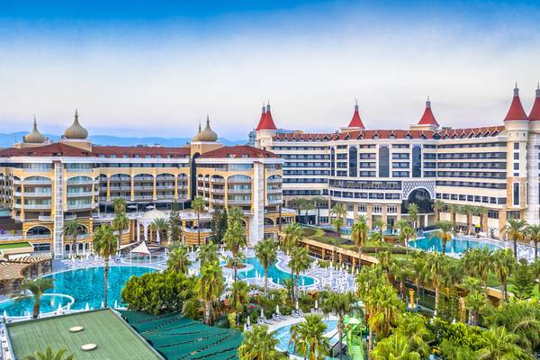 Außenansicht des Kirman Leodikya Resorts mit großen Swimmingpools und Palmen