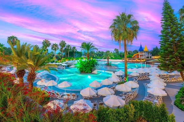 Außenpool des Kirman Leodikya Resorts bei Sonnenuntergang mit buntem Himmel