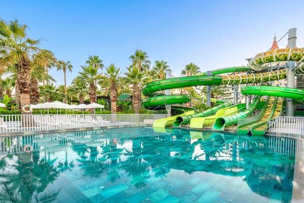 Wasserrutschen im Kirman Leodikya Resort mit einem großen Pool und Liegestühlen.