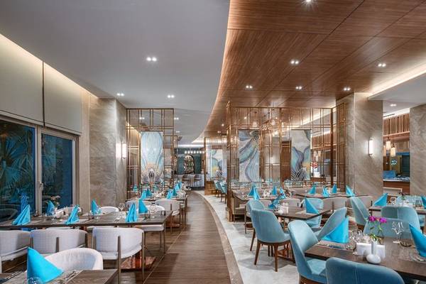 Restaurantbereich im Kirman Leodikya Resort mit modernen Möbeln und blauen Akzenten.
