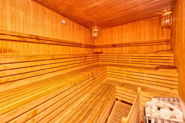 Saunaraum im Kirman Leodikya Resort Hotel mit Holzbänken und einer Wanduhr.