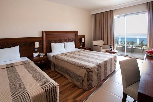 Zimmer im Kirman Leodikya Resort mit zwei Betten, Balkon und Meerblick.