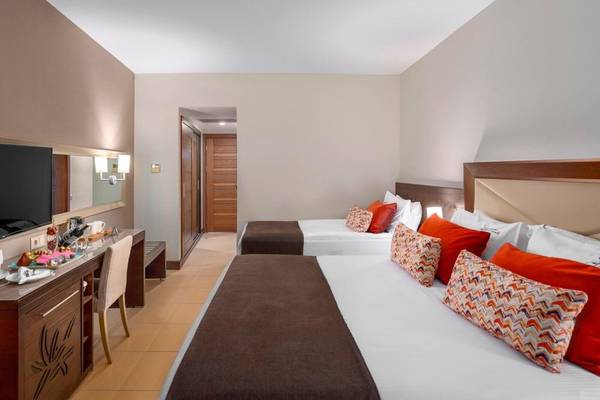 Innenansicht eines Hotelzimmers im Kirman Leodikya Resort mit zwei Betten und Dekor.