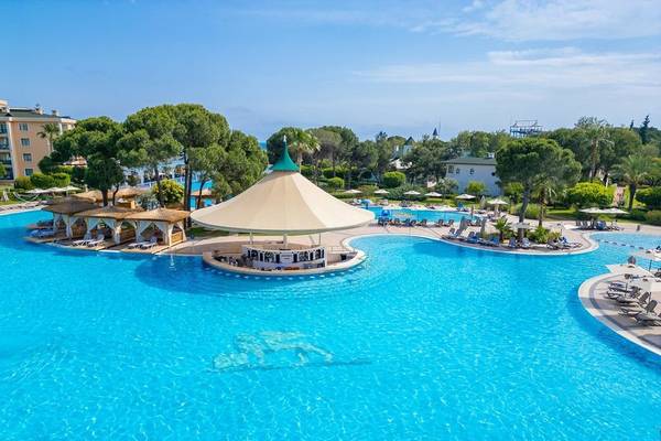 Außenansicht des großen Außenpools des Ducale Lara Hotels mit Loungebereich und Bar.