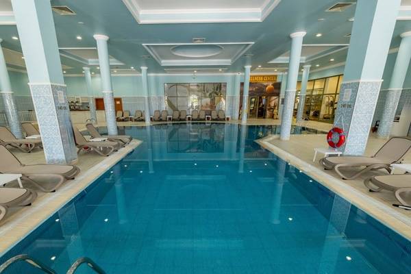 Innenpool des Ducale Lara Hotels mit blauen Wänden und vielen Liegestühlen