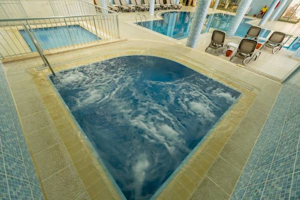 Innenpool des Ducale Lara Hotels mit fließendem Wasser und blauen Fliesen