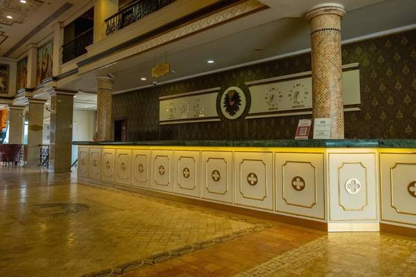 Empfangsbereich des Ducale Lara Hotels mit Marmortheke und kunstvollen Wanddekorationen.