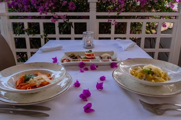 Ein Tisch auf dem Balkon des Ducale Lara Hotels, gedeckt mit Tellern, Besteck und einem Kerzenlicht.