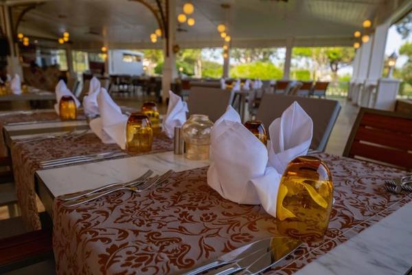 Ein Restauranttisch im Ducale Lara Hotel mit Servietten, Besteck und Gläsern.