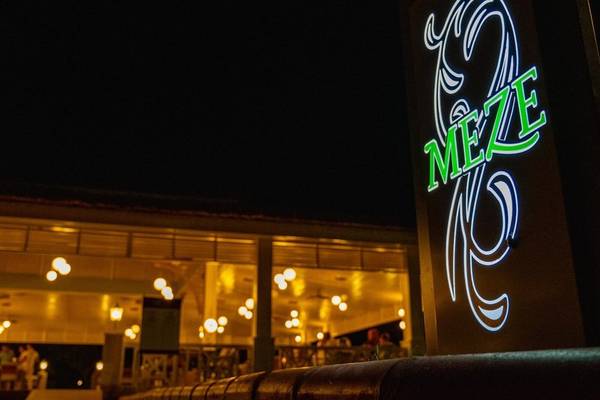 Nachtansicht des Ducale Lara Hotels mit leuchtendem Neon-Schild 'Meze'.