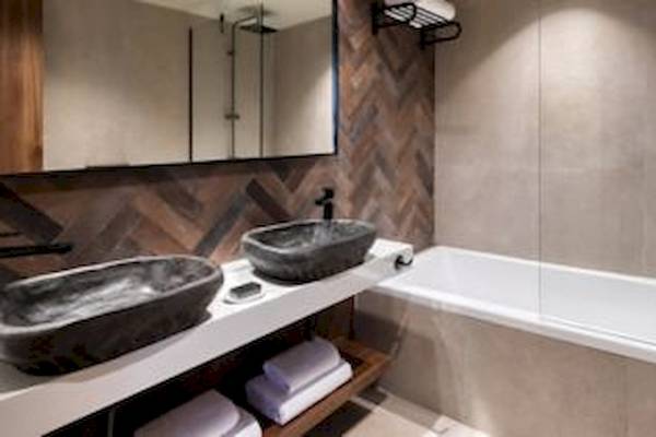Ein Badezimmer mit zwei Waschbecken, einer Badewanne und einer Dusche im Domes Aulus Zante Hotel.