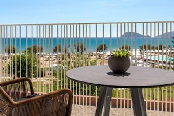 Ein Balkon mit Tisch und Stuhl bietet Aussicht auf das Meer und eine Bergkette.
