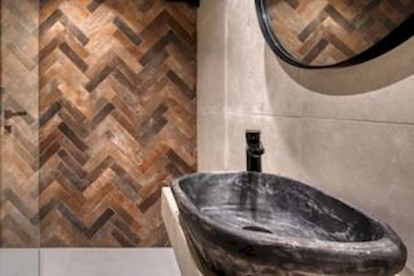 Badezimmer mit braunem Holz-Herzmuster an der Wand und einer schwarzen Marmor-Waschbecken.