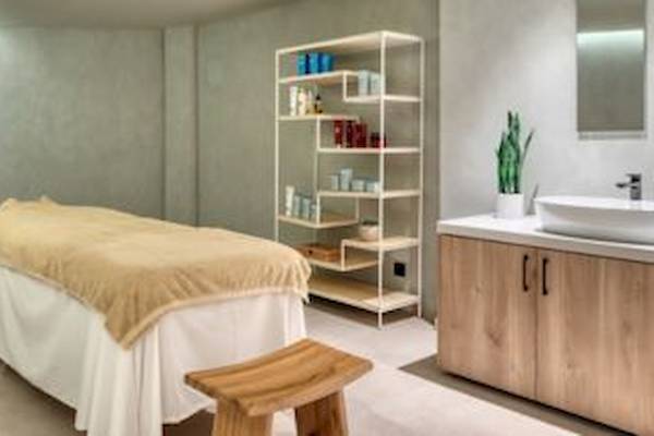 Massageraum im Domes Aulus Zante Hotel mit Massageliege, Regal, Waschbecken und Pflanze.