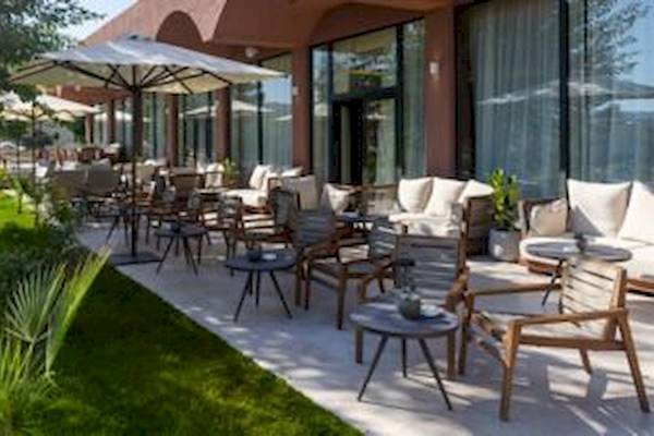 Terrasse des Domes Aulus Zante Hotels mit Tischen, Stühlen und Sonnenschirmen.