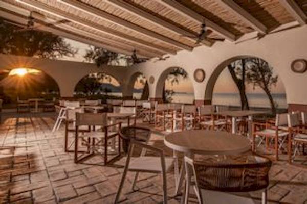 Außenbereich des Domes Aulus Zante Hotels mit Tischen und Stühlen und Blick auf den Sonnenuntergang.