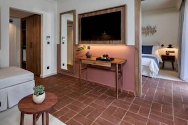 Suitenzimmer im Domes Aulus Zante mit Fernseher, Tisch, Sofa und Schlafzimmer.