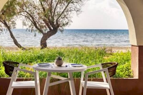 Aussicht auf den Außenbereich des Domes Aulus Zante Hotels mit einem Tisch und Stühlen vor dem Meer.