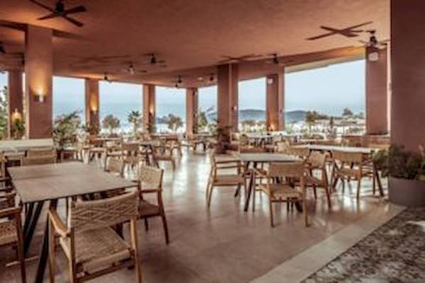 Innenbereich des Domes Aulus Zante Hotels mit mehreren Tischen und Stühlen und Blick auf das Meer.