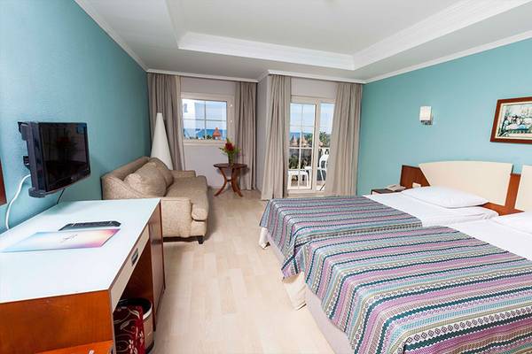 Hotelzimmer im Belek Beach Resort mit zwei Betten, Fernseher, Couch und Balkon.