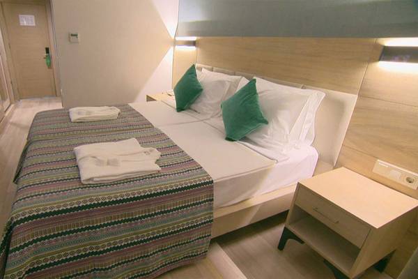 Doppelbettzimmer im Belek Beach Resort Hotel mit grünen Kissen und Bettwäsche.
