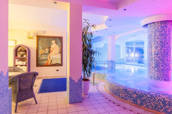 Wellnessbereich des Baia Imperiale Hotels mit Sauna, Tisch, Stühlen und Kunstwerk an der Wand.