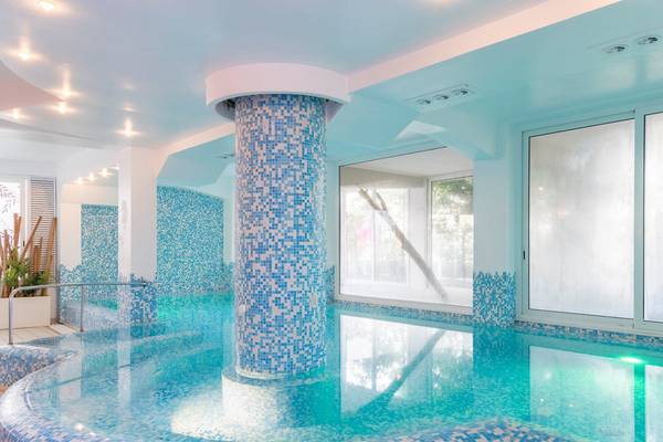 Innenpool des Baia Imperiale Hotels mit blauen Mosaikfliesen und zentraler Säule