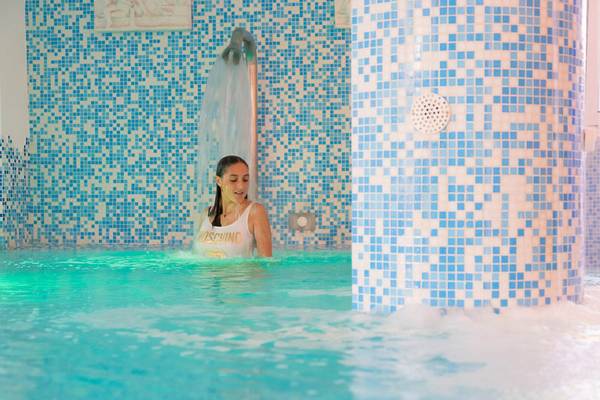 Eine Frau steht in einem blau gefliesten Schwimmbad des Baia Imperiale Hotels.