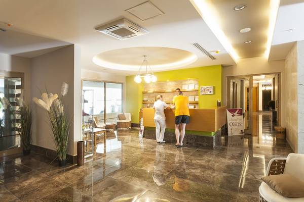 Die Rezeption des Belek Beach Resort Hotels mit zwei Mitarbeitern an der Theke.