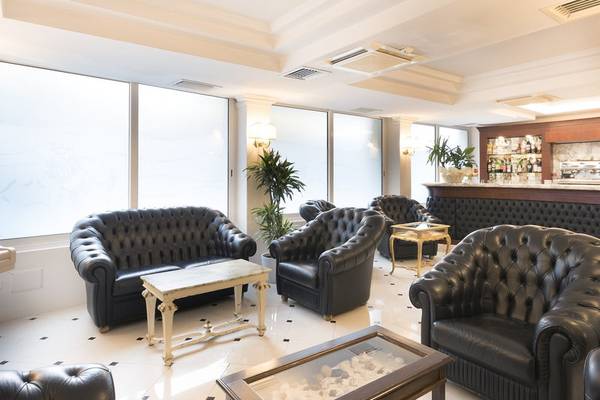 Lobby des Baia Imperiale Hotels mit schwarzen Ledersofas, Tischen und einer Bar.