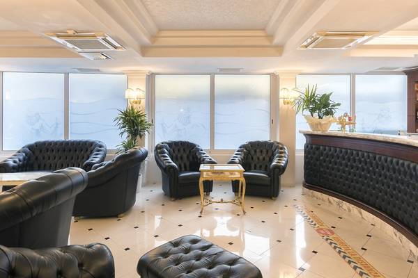 Lobby des Baia Imperiale Hotels mit schwarzen Ledersofas, einem goldenen Tisch und großen Fenstern.