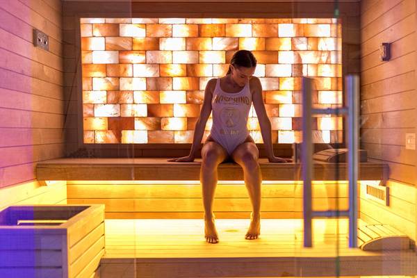 Frau sitzt in einer Sauna des Baia Imperiale Hotels mit einer beleuchteten Wand im Hintergrund.