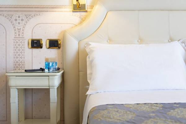 Schlafzimmer im Baia Imperiale Hotel mit weißem Kopfteil, Nachttisch und Kissen.