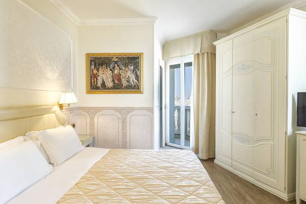 Schlafzimmer im Baia Imperiale Hotel mit Doppelbett, Kunstwerk an der Wand und Terrassentür.