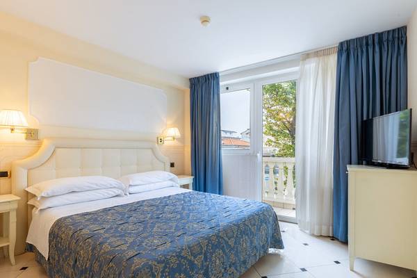 Schlafzimmer im Baia Imperiale Hotel mit Doppelbett, Fernseher und Balkon.