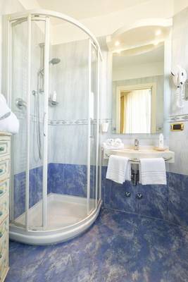 Badezimmer im Baia Imperiale Hotel mit Dusche, Spiegel und Handtüchern.
