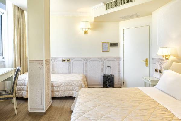 Innenansicht eines Doppelzimmers im Baia Imperiale Hotel mit zwei Betten, einem Schreibtisch und einem Gepäckstück.