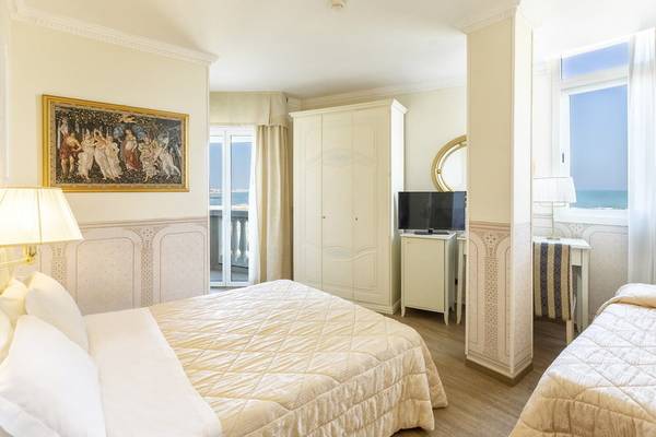 Schlafzimmer im Baia Imperiale Hotel mit zwei Betten, Fernseher, Schrank und Meerblick.