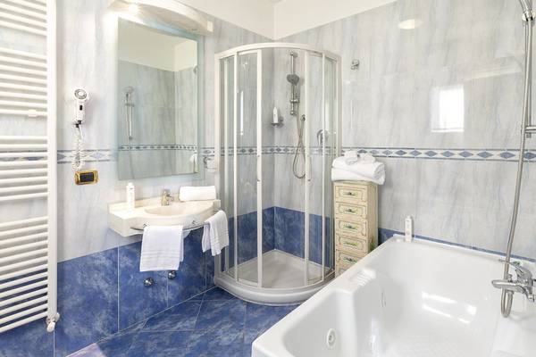 Badezimmer im Baia Imperiale Hotel mit Badewanne, Dusche, Waschbecken und Handtüchern