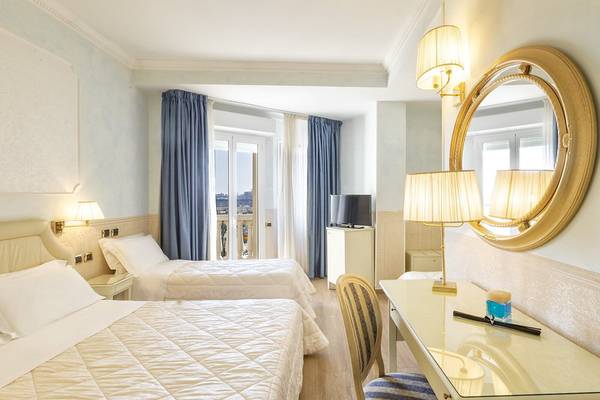 Doppelzimmer im Baia Imperiale Hotel mit zwei Betten, Schreibtisch, ovalem Spiegel und Balkon.
