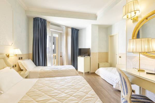 Doppelzimmer im Baia Imperiale Hotel mit zwei Betten, Fernseher, Schreibtisch und goldenen Lampen